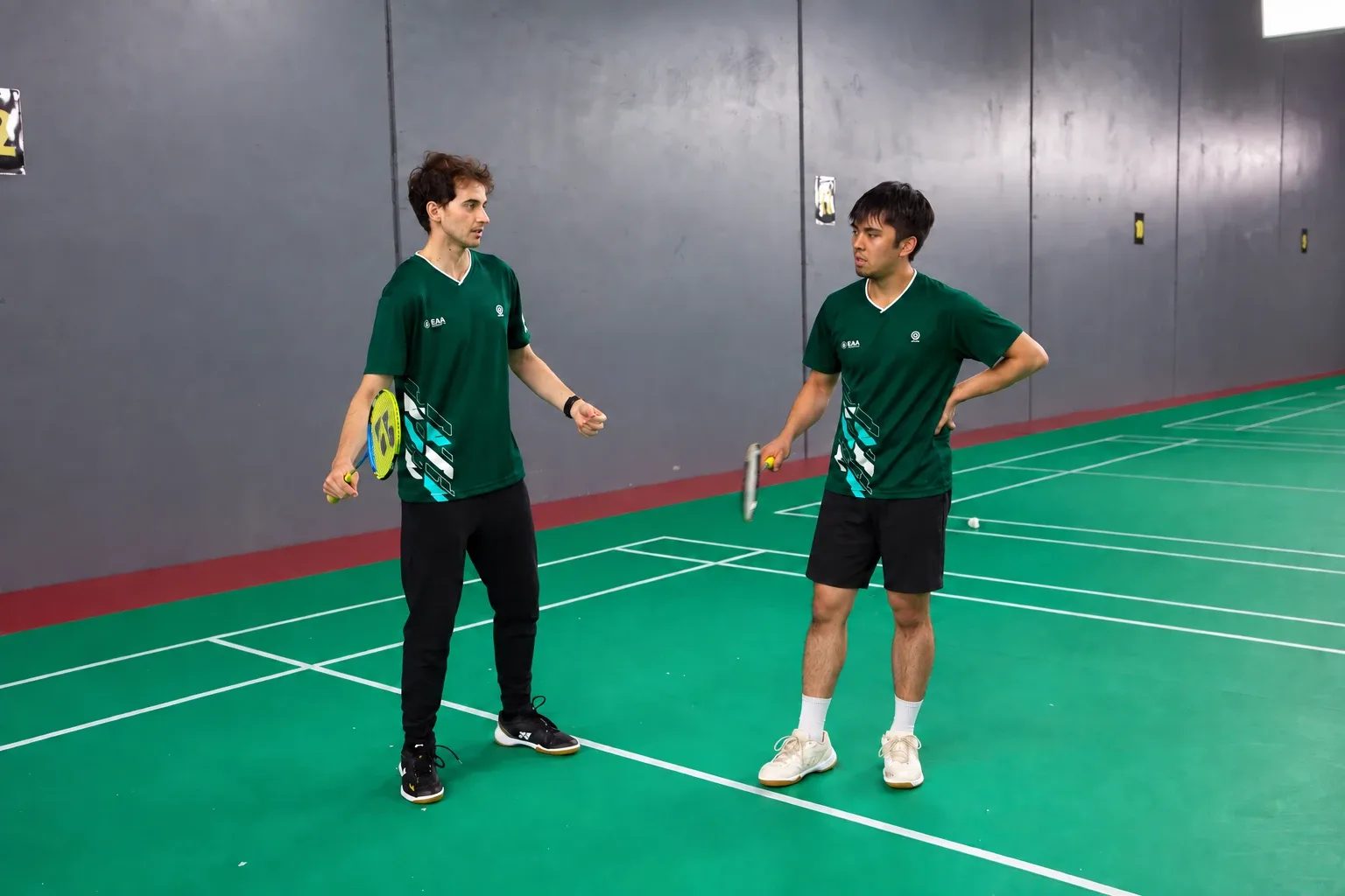 Two adult players in EAA kit talking tactics between rallies