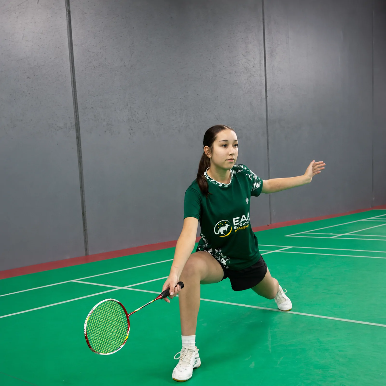A junior player lunging for a low shuttle