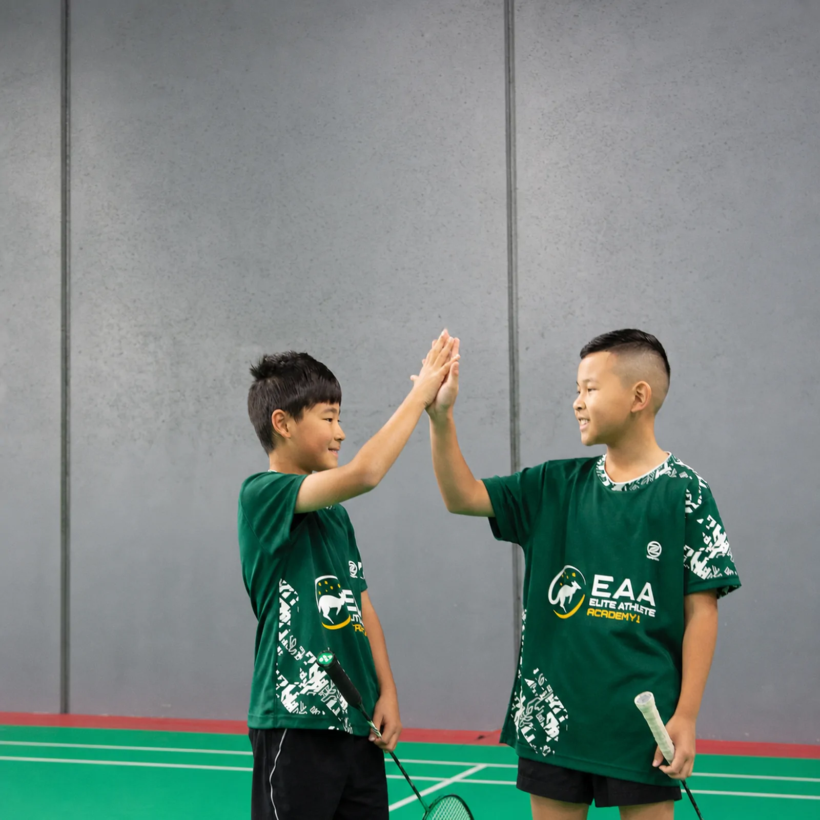 Two young players high-five on court in EAA kit